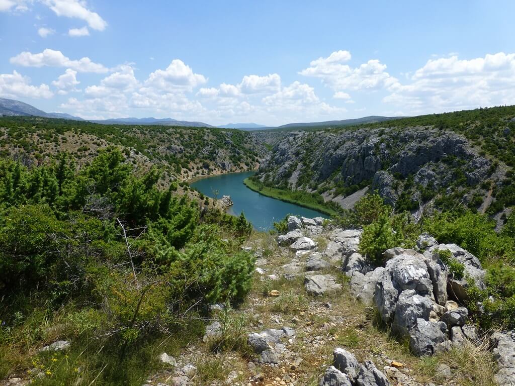 Rijeka Zrmanja poznata je po svojoj divljoj ljepoti, a njezini slapovi spadaju među najimpresivnije slapove u Hrvatskoj. Na fotografiji se vidi meandar rijeke okružen stijenama i netaknutom prirodom, što ovo područje čini idealnim za izlete i avanture.